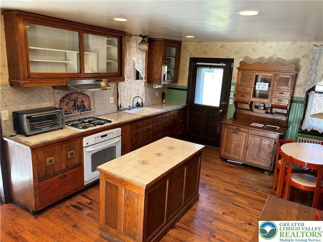 kitchen featuring a sink, white appliances, a toaster, under cabinet range hood, and tile counters