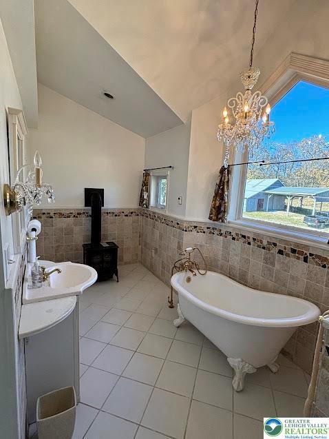 full bathroom with lofted ceiling, tile walls, tile patterned floors, and a soaking tub