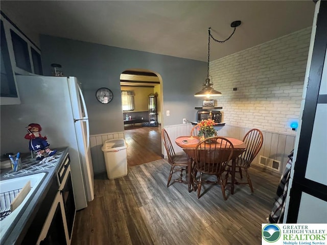 3426 Wilson Ave, South Whitehall Twp, PA 18069 - dining room with dark wood finished floors, brick wall, visible vents, a wainscoted wall, and arched walkways