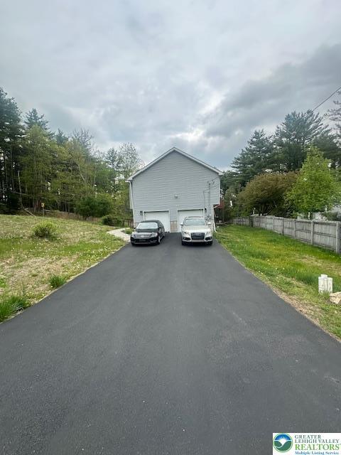 exterior space featuring fence, a garage, and aphalt driveway