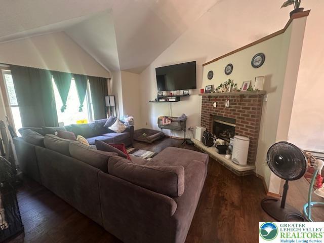 living room with a fireplace, vaulted ceiling, and wood finished floors