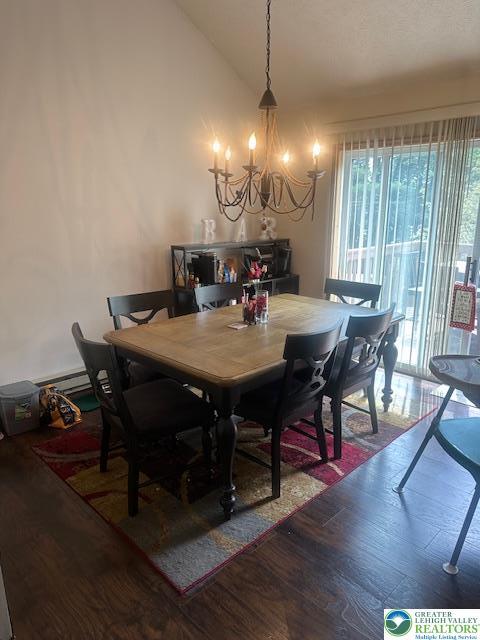 dining room featuring wood finished floors, lofted ceiling, and a notable chandelier