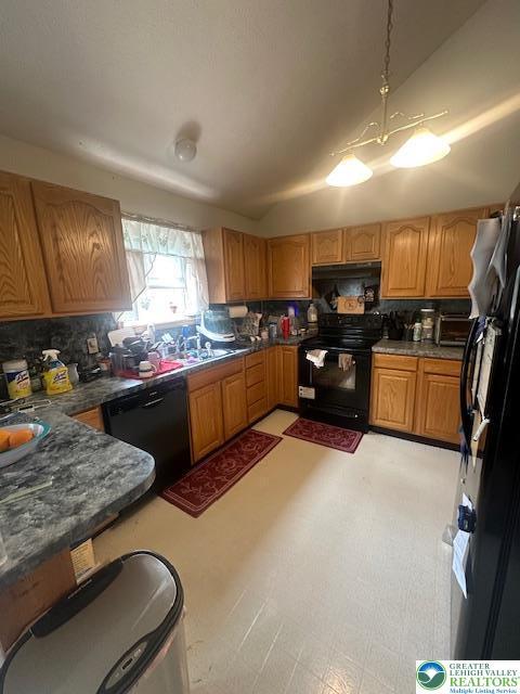 kitchen featuring black appliances, dark countertops, a sink, and decorative backsplash