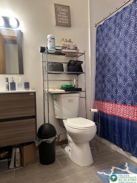 bathroom featuring toilet, vanity, and a shower with curtain