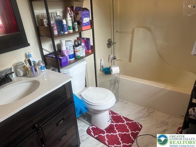 bathroom featuring toilet, tub / shower combination, marble finish floor, and vanity