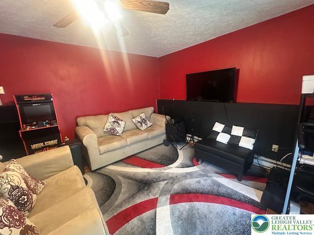 carpeted living area with a textured ceiling and a ceiling fan