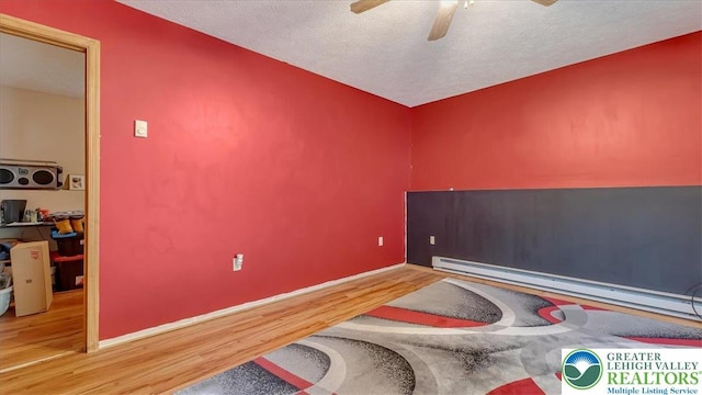 838 Cayuga Way, Stroud Twp, PA 18360 - unfurnished room with wood finished floors, ceiling fan, baseboard heating, and a textured ceiling