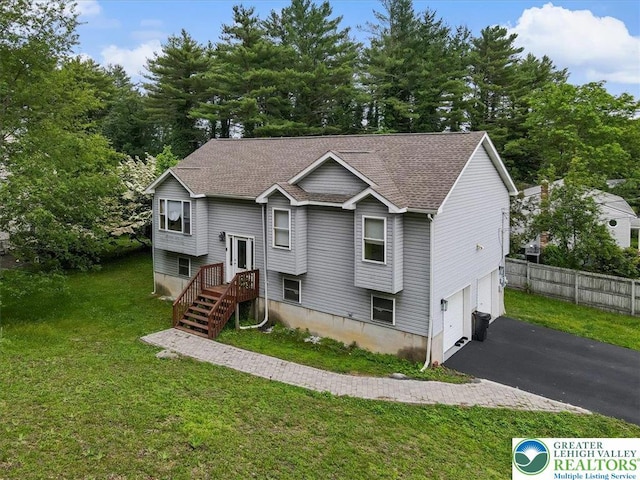 838 Cayuga Way, Stroud Twp, PA 18360 - split foyer home with asphalt driveway, an attached garage, view of wooded area, and roof with shingles