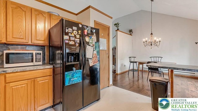 838 Cayuga Way, Stroud Twp, PA 18360 - kitchen with black fridge, white microwave, a chandelier, vaulted ceiling, and decorative light fixtures