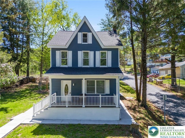 view of front of house with a porch, roof with shingles, fence, and a front yard
