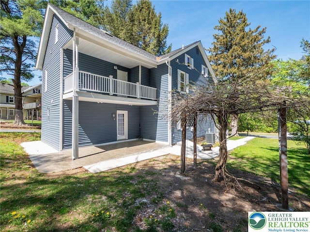 exterior space with a yard, a patio area, central AC unit, and a balcony