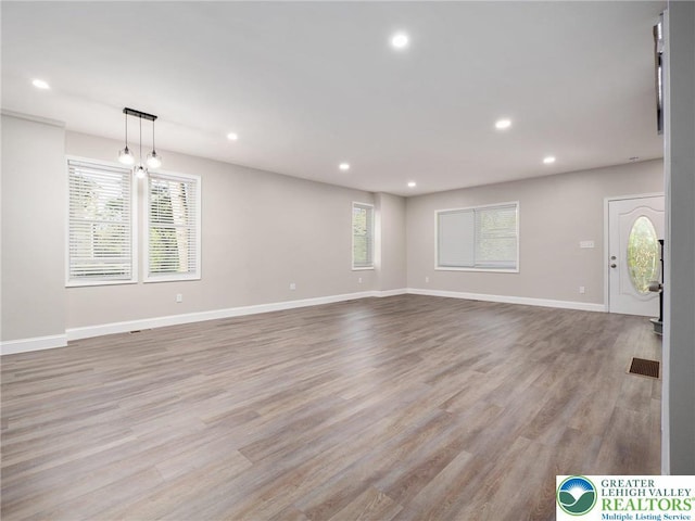 unfurnished living room featuring baseboards, visible vents, recessed lighting, and wood finished floors