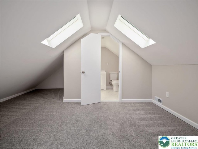 bonus room with carpet flooring, lofted ceiling with skylight, and visible vents