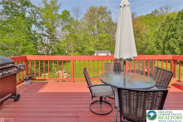 wooden deck with a grill, outdoor dining space, and a lawn