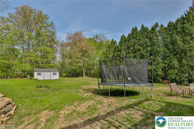 view of yard with a trampoline and an outbuilding