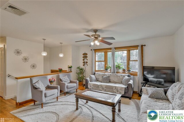 living room featuring ceiling fan, light wood-style floors, and visible vents