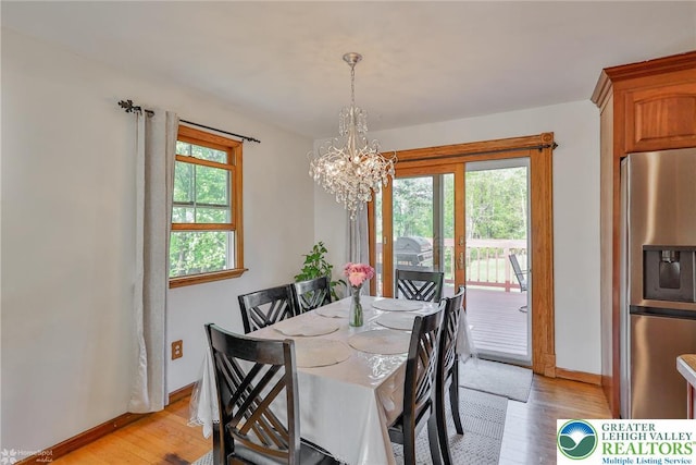 dining room featuring light wood-type flooring, a chandelier, and baseboards