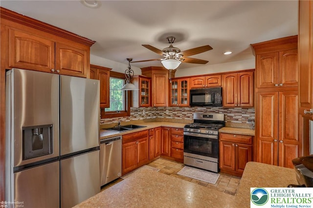 kitchen with light countertops, appliances with stainless steel finishes, brown cabinetry, and a sink