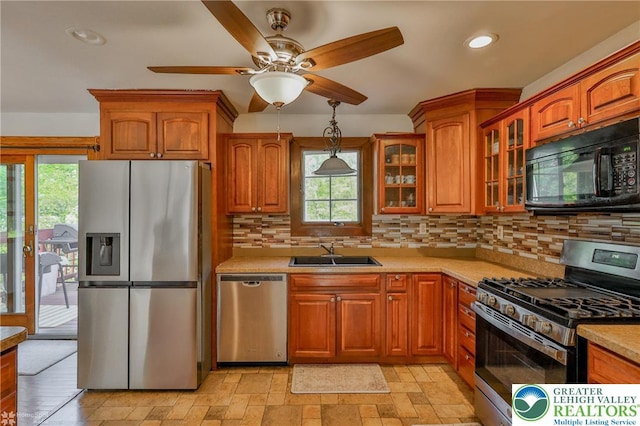 kitchen with brown cabinetry, light countertops, appliances with stainless steel finishes, and a sink