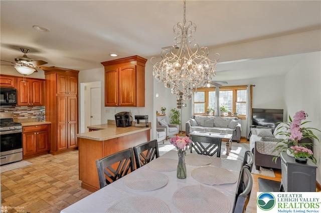 dining space with recessed lighting, stone finish floor, and ceiling fan with notable chandelier