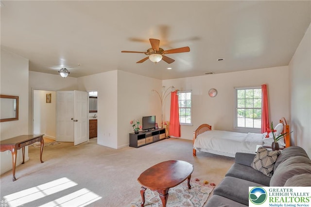 bedroom featuring ensuite bathroom, baseboards, visible vents, ceiling fan, and light carpet