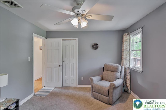 sitting room featuring carpet, baseboards, a ceiling fan, and visible vents