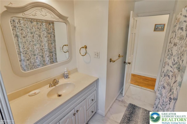 bathroom with baseboards, marble finish floor, and vanity