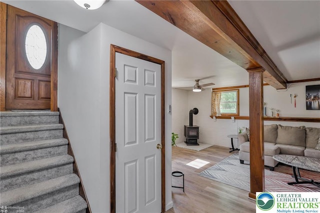 stairs with a wood stove, wood finished floors, and ceiling fan