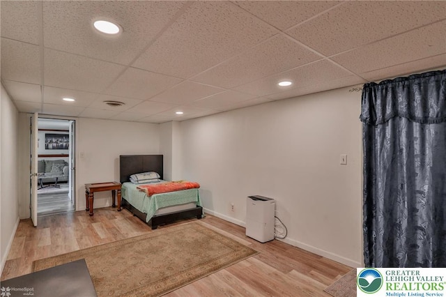 bedroom featuring a drop ceiling, wood finished floors, visible vents, baseboards, and recessed lighting