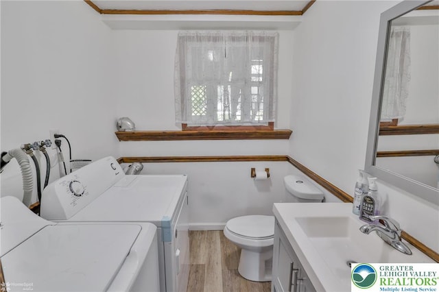 bathroom featuring washing machine and clothes dryer, vanity, toilet, and wood finished floors