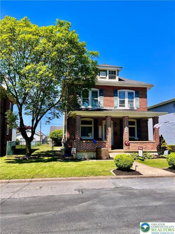 american foursquare style home featuring brick siding, a porch, and central AC