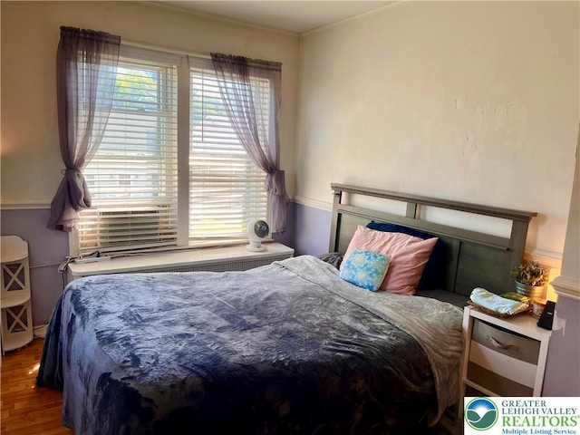 bedroom featuring wood finished floors, multiple windows, and crown molding