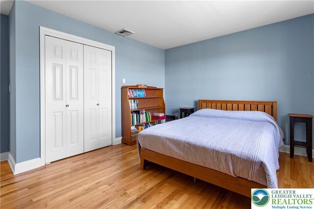 bedroom with baseboards, a closet, light wood-type flooring, and visible vents