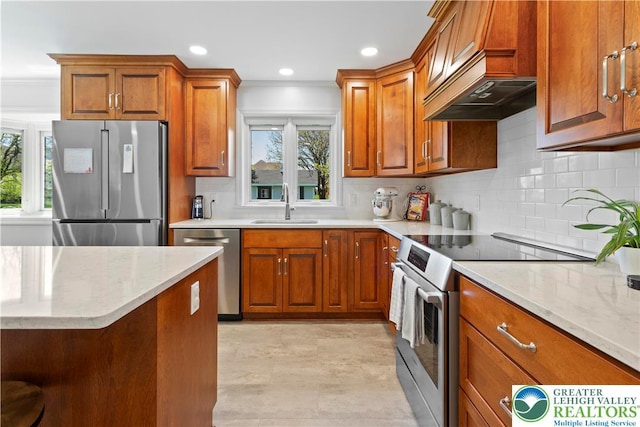 kitchen featuring stainless steel appliances, brown cabinetry, light stone countertops, and a sink