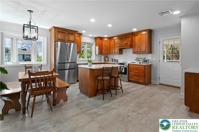 kitchen with brown cabinets, ornamental molding, visible vents, light countertops, and appliances with stainless steel finishes