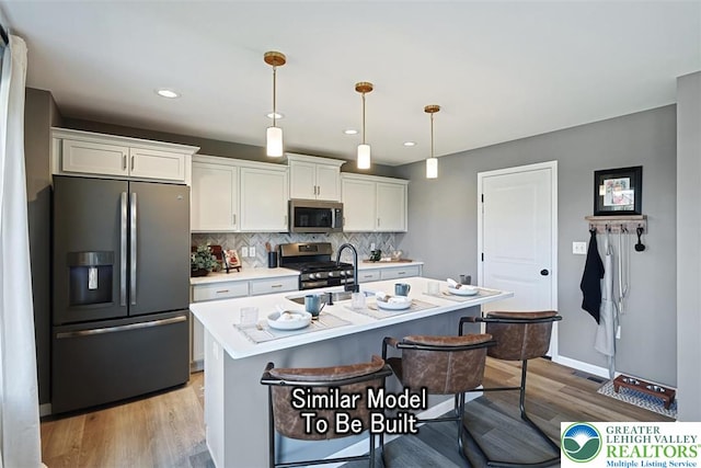 kitchen with light countertops, light wood finished floors, white cabinets, and appliances with stainless steel finishes