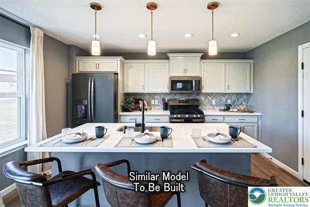 kitchen with a breakfast bar area, a sink, plenty of natural light, backsplash, and appliances with stainless steel finishes