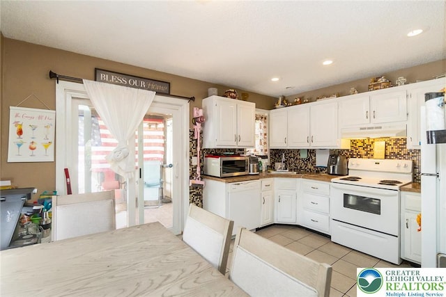 1231 Kensington Dr, Stroud Twp, PA 18301 - kitchen featuring under cabinet range hood, light tile patterned floors, white appliances, white cabinetry, and decorative backsplash