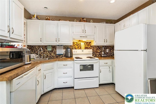 1231 Kensington Dr, Stroud Twp, PA 18301 - kitchen featuring under cabinet range hood, light tile patterned floors, white appliances, a sink, and white cabinetry