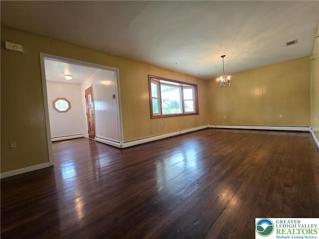 spare room with a baseboard heating unit, an inviting chandelier, visible vents, and dark wood-type flooring