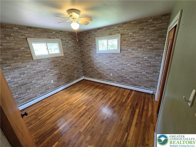 spare room with baseboard heating, ceiling fan, and dark wood-type flooring