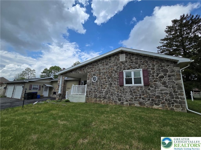 single story home featuring a garage, a front lawn, stone siding, and driveway