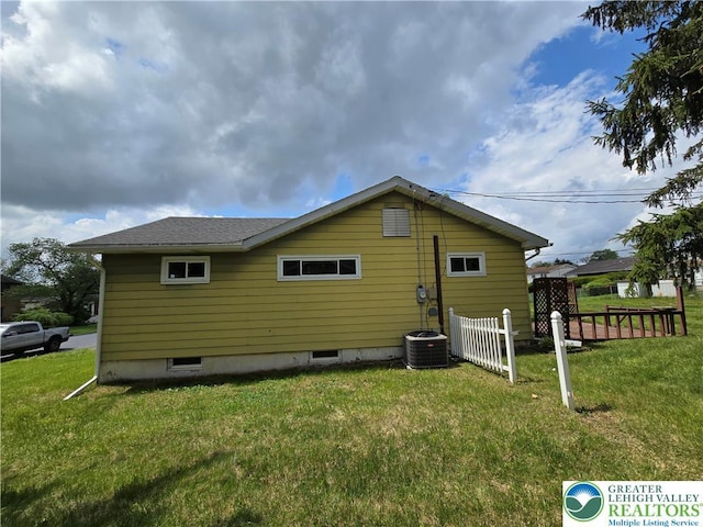 back of property featuring fence, a shingled roof, and a lawn
