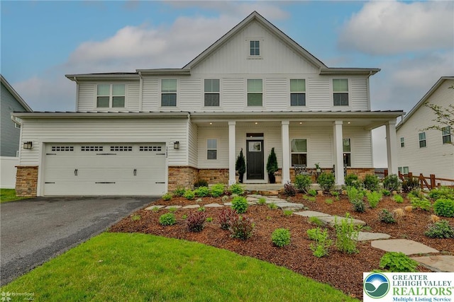 view of front of home featuring covered porch, aphalt driveway, stone siding, a garage, and board and batten siding