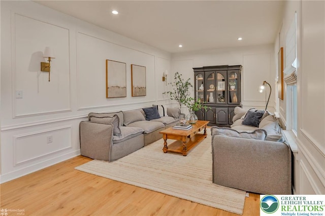 living room featuring a decorative wall, recessed lighting, and wood finished floors