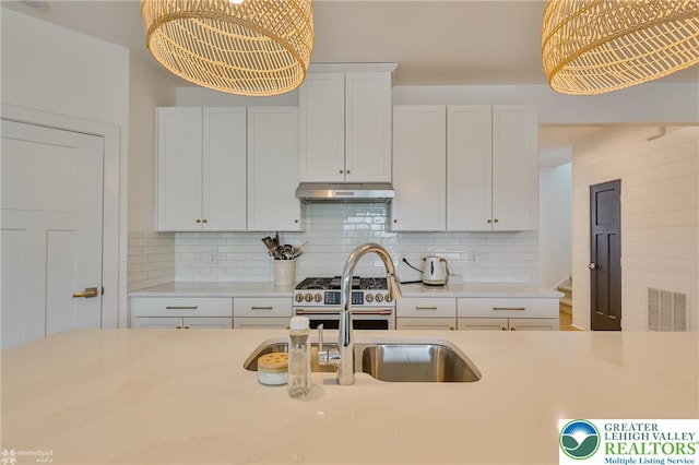kitchen with visible vents, under cabinet range hood, decorative backsplash, range with two ovens, and light countertops