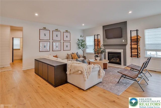 living room with a fireplace, light wood-type flooring, and recessed lighting
