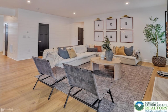 living area with baseboards, recessed lighting, and light wood-type flooring