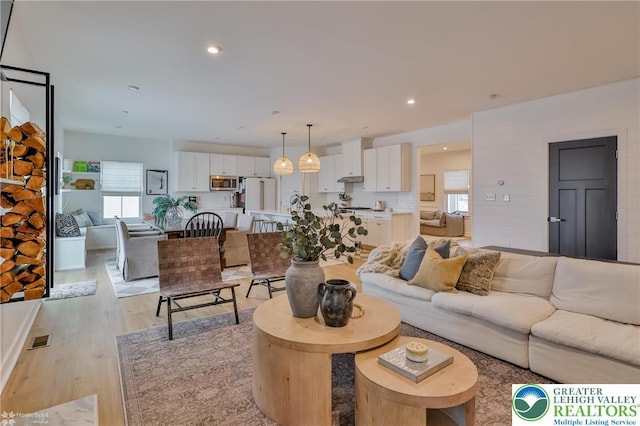 living area with recessed lighting, light wood finished floors, and visible vents