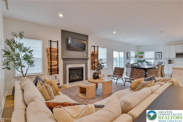 living room featuring baseboards, a fireplace, light wood-style flooring, and recessed lighting